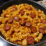 Cajun pasta with smoked sausage and rotini in a skillet, coated in creamy spicy sauce