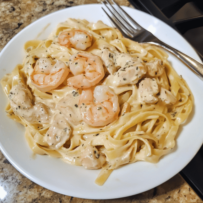 Creamy fettuccine alfredo with shrimp and chicken served on a rustic table